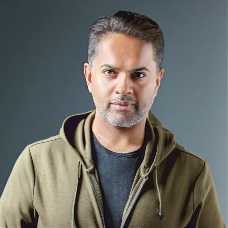 Portrait of IGNITE Beats in an olive hooded jacket against a grey background